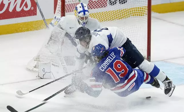 Finland defenseman Mitja Jokinen (2) takes down United States forward Trevor Connelly (19) in front of Finland goaltender Petteri Rimpinen, top, during first-period IIHF World Junior Hockey Championship gold medal game action in Ottawa, Ontario, Sunday, Jan. 5, 2025. (Adrian Wyld/The Canadian Press via AP)