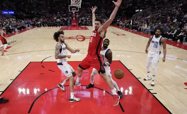 Houston Rockets' Alperen Sengun (28) loses the ball as Dallas Mavericks' Kyrie Irving (11) and Dereck Lively II defend during the first half of an NBA basketball game Wednesday, Jan. 1, 2025, in Houston. (AP Photo/David J. Phillip)