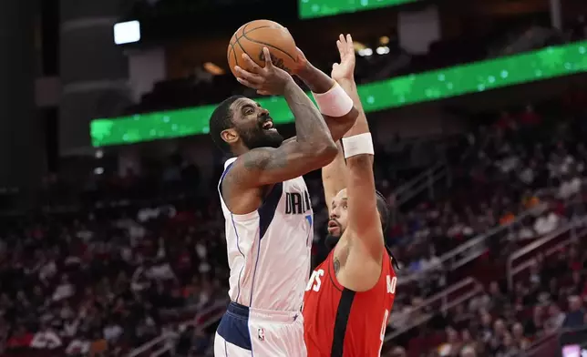 Dallas Mavericks' Kyrie Irving, left, shoots as Houston Rockets' Dillon Brooks defends during the first half of an NBA basketball game Wednesday, Jan. 1, 2025, in Houston. (AP Photo/David J. Phillip)