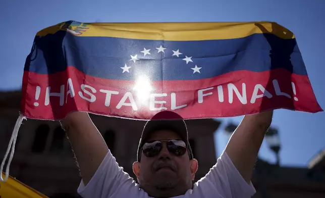 Leo Zambrano, supporter of Venezuela's opposition leader Edmundo Gonzalez Urrutia, holds a Venezuela's flag at Plaza de Mayo, outside the government house where he meets with Argentine President Javier Milei in Buenos Aires, Argentina, Saturday, Jan. 4, 2025. Gonzalez, who claims he won the 2024 presidential election and is recognized by some countries as the legitimate president-elect, traveled from exile in Madrid to Argentina. (AP Photo/Natacha Pisarenko)