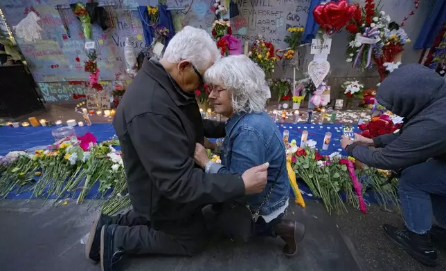 Long Island, New York residents Louis Tenedorio, left, and his wife, Cathy Tenedorio, embrace on by a memorial Bourbon Street and Canal Street in New Orleans, Saturday, Jan. 4, 2025, where their son, Matthew Tenedorio, was killed as one of the victims of the New Year's Day deadly truck attack and shooting. (AP Photo/Matthew Hinton)