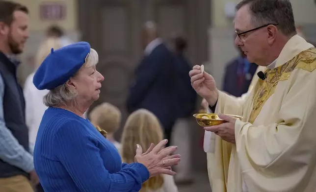Father Patrick Williams gives a blessing and Eucharist bread to a parishioner at St. Louis Cathedral during a mass about the victims of the New Year's Day deadly truck attack and shooting on Bourbon Street not far from the cathedral in the French Quarter in New Orleans, Sunday, Jan. 5, 2025. (AP Photo/Matthew Hinton)