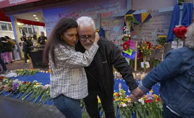 Long Island, New York residents Louis Tenedorio is hugged by family friend Angelique Whittington, left, while holding the hand of his wife, Cathy Tenedorio, by a memorial Bourbon Street and Canal Street in New Orleans, Saturday, Jan. 4, 2025, where their son, Matthew Tenedorio, was killed as one of the victims of the New Year's Day deadly truck attack and shooting. (AP Photo/Matthew Hinton)
