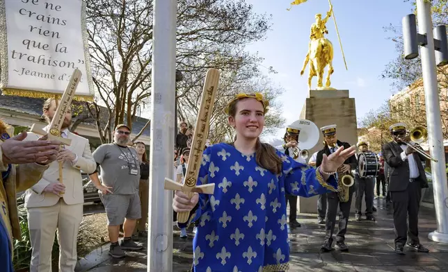 A procession of Krewe de Jeanne d'Arc represented by 2025 Maid of Honor Life Sacco, center, and the Soul Heirs Brass Band dances by a golden statue of St. Joan of Arc in the French Quarter after leaving St. Louis Cathedral in New Orleans, Sunday, Jan. 5, 2025, after a mass honoring victims of the New Year's Day deadly truck attack and shooting not far from the cathedral in the French Quarter. (AP Photo/Matthew Hinton)