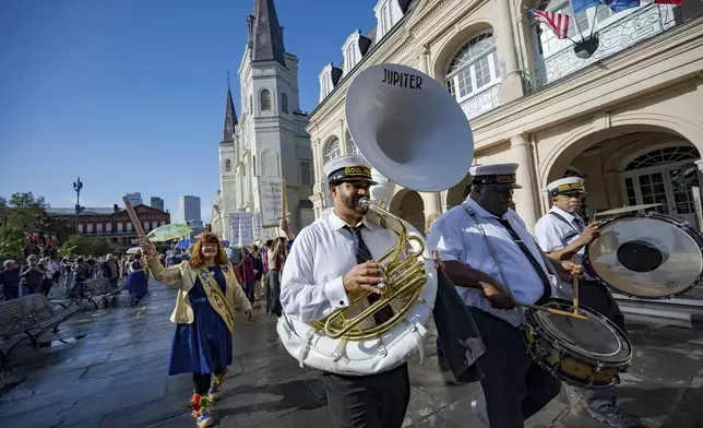A procession of Krewe de Jeanne d'Arc represented by co-captain Antoinette de Alteriis, left, and the Soul Heirs Brass Band leaves St. Louis Cathedral in New Orleans, Sunday, Jan. 5, 2025, after a mass honoring the victims of the New Year's Day deadly truck attack and shooting not far from the cathedral in the French Quarter. (AP Photo/Matthew Hinton)