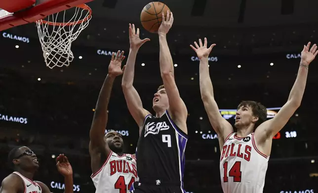 Sacramento Kings' Kevin Huerter (9) goes up to shoot against Chicago Bulls' Patrick Williams (44), Matas Buzelis (14) and Jevon Carter, left, during the first half of an NBA basketball game on Sunday, Jan. 12, 2025, in Chicago. (AP Photo/Paul Beaty)