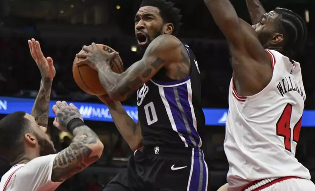 Sacramento Kings' Malik Monk (0) goes up to shoot against Chicago Bulls' Patrick Williams (44) and Lonzo Ball, left, during the first half of an NBA basketball game Sunday, Jan. 12, 2025, in Chicago. (AP Photo/Paul Beaty)