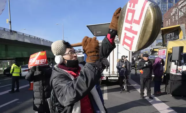 A protester beats a traditional Korean gong during a rally demanding the arrest of impeached South Korean President Yoon Suk Yeol near the presidential residence in Seoul, South Korea, Thursday, Jan. 9, 2025. The letters read "Dismiss." (AP Photo/Ahn Young-joon)