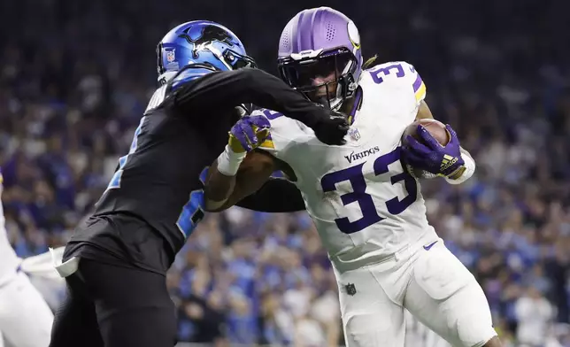 Minnesota Vikings running back Aaron Jones (33) is hit by Detroit Lions cornerback Amik Robertson (21) on a run during the second half of an NFL football game Sunday, Jan. 5, 2025, in Detroit. (AP Photo/Rey Del Rio)