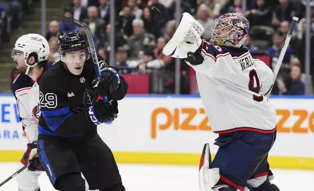 Columbus Blue Jackets goaltender Elvis Merzlikins (90) reaches for the puck in front of Toronto Maple Leafs' Pontus Holmberg (29) during second period NHL hockey action in Toronto on Wednesday, January 22, 2025. (Frank Gunn/The Canadian Press via AP)