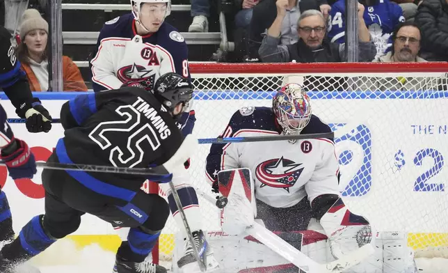 Columbus Blue Jackets goaltender Elvis Merzlikins (90) makes a save on Toronto Maple Leafs' Conor Timmins (25) as Blue Jackets' Zach Werenski (8) defends during first period NHL hockey action in Toronto on Wednesday, Jan. 22, 2025. (Frank Gunn/The Canadian Press via AP)