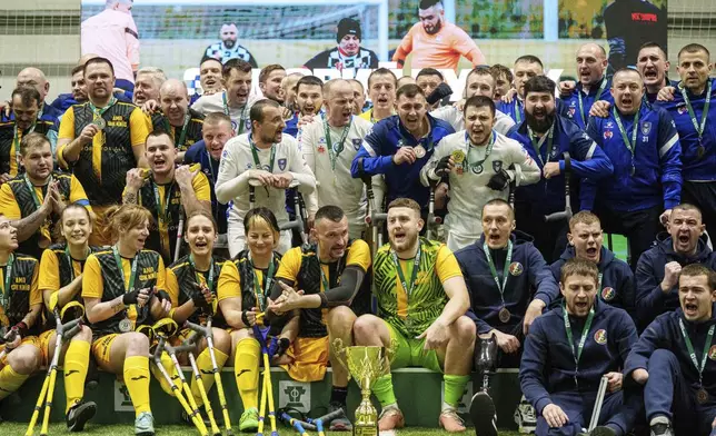 Soccer players pose for photo in the end of the first football tournament for war-wounded amputees in Kyiv, Ukraine, Jan. 12, 2025. (AP Photo/Evgeniy Maloletka)