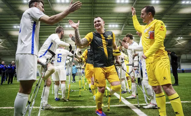 Soccer players of AMP FC Kyiv and Pokrova FC-2 greets each other during the first football tournament for war-wounded amputees in Kyiv, Ukraine, Jan. 12, 2024. (AP Photo/Evgeniy Maloletka)