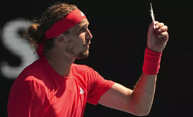 Alexander Zverev of Germany reacts as he holds a feather during his quarterfinal match against Tommy Paul of the U.S. during their quarterfinal match at the Australian Open tennis championship in Melbourne, Australia, Tuesday, Jan. 21, 2025. (AP Photo/Vincent Thian)