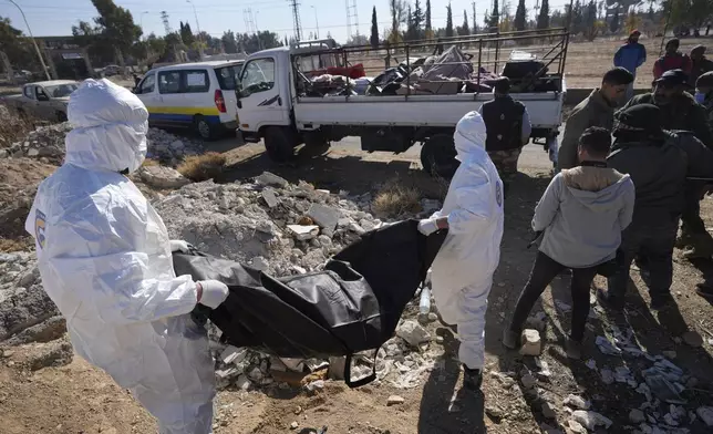 Members of the Syrian Civil Defense carry one of several bodies, and human remains, discovered near Damascus International Airport, in Damascus, Syria, on Dec. 16, 2024. (AP Photo/Hussein Malla)