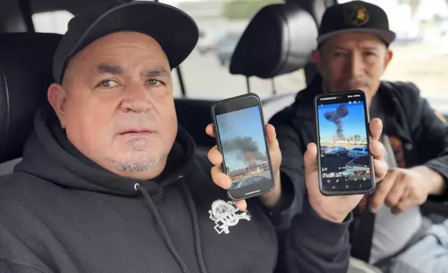 Daniel Villalbazo, left and Efrain Romero show photos on their mobile phones, Friday, Jan. 3, 2025, in Fullerton, Calif., after witnessing a plane crash the day before at the warehouse of a commercial building where the accident happened. (AP Photo/Damian Dovarganes)