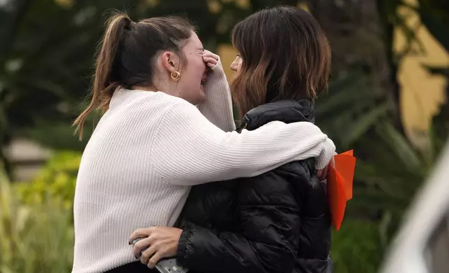 A mourner weeps as they are embraces before a memorial service at First Christian Church in Huntington Beach, Calif., Friday, Jan. 3, 2025, for those killed in a small plane crash the day before. (AP Photo/Damian Dovarganes)