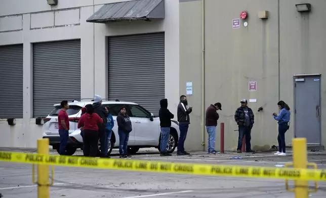 Workers line up to enter a warehouse of a commercial furniture factory to collect their belongings Friday, Jan. 3, 2025, in Fullerton, Calif., where a small plane crashed the day before. (AP Photo/Damian Dovarganes)