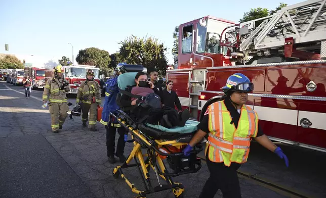 A woman is carried on a stretcher near the site of a plane crash, Thursday, Jan. 2, 2025, in Fullerton, Calif. (AP Photo/Kyusung Gong)