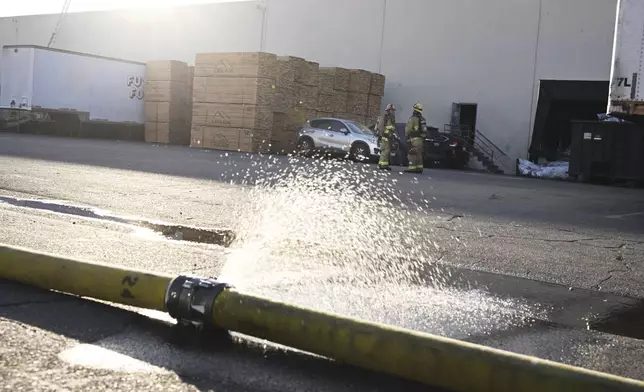 Firefighters stage outside a building where a plane crash occurred, Thursday, Jan. 2, 2025, in Fullerton, Calif. (AP Photo/Kyusung Gong)