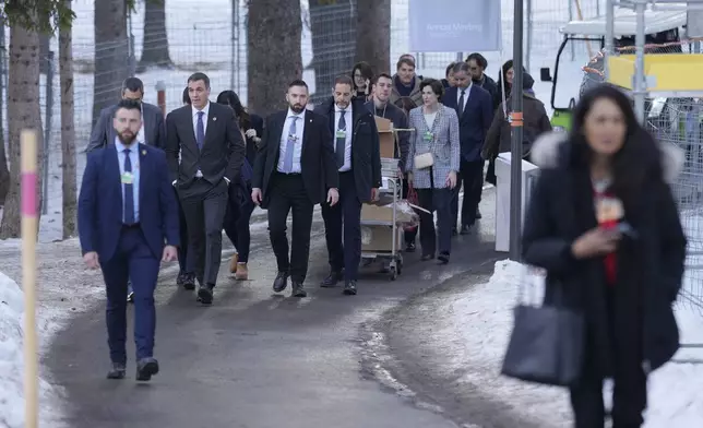Prime Minister of Spain Pedro Sanchez, left in background, walks in the snow at the Annual Meeting of World Economic Forum in Davos, Switzerland, Wednesday, Jan. 22, 2025. (AP Photo/Markus Schreiber)
