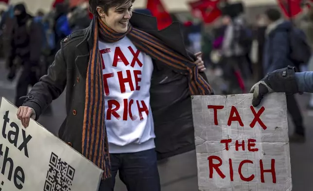 Activist Marlene Engelhorn holds banners during a protest at the Meeting of World Economic Forum in Davos, Switzerland, Thursday, Jan. 23, 2025. (Michael Buholzer/Keystone via AP)