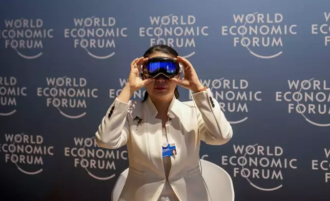 A woman uses virtual reality glasses the Annual Meeting of World Economic Forum in Davos, Switzerland, Wednesday, Jan. 22, 2025. (AP Photo/Markus Schreiber)