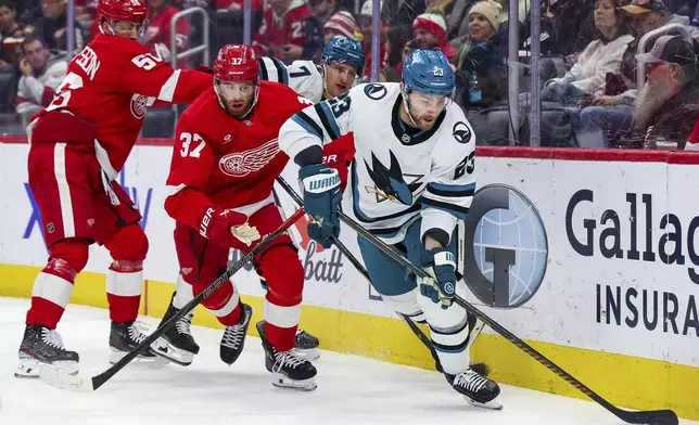 San Jose Sharks forward Barclay Goodrow (23) skates the puck out from behind the net against Detroit Red Wings forward J.T. Compher (37) in the first period of an NHL hockey game, Tuesday, Jan. 14, 2025, in Detroit. (AP Photo/Mike Mulholland)
