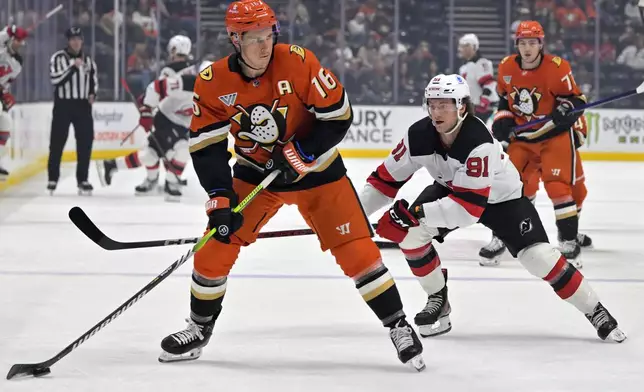 Anaheim Ducks center Ryan Strome, left, passes the puck in front of New Jersey Devils center Dawson Mercer, front right, during the first period of an NHL hockey game Tuesday, Dec. 31, 2024, in Anaheim, Calif. (AP Photo/Jayne Kamin-Oncea)