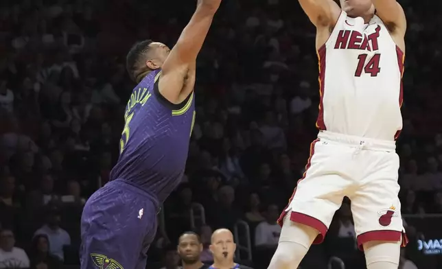 Miami Heat guard Tyler Herro (14) shoots as New Orleans Pelicans guard Dejounte Murray, left, defends during the first half of an NBA basketball game, Wednesday, Jan. 1, 2025, in Miami. (AP Photo/Lynne Sladky)