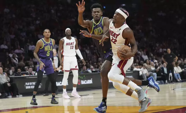 Miami Heat forward Jimmy Butler (22) drives to the basket and is fouled by New Orleans Pelicans center Yves Missi, left, during the first half of an NBA basketball game, Wednesday, Jan. 1, 2025, in Miami. (AP Photo/Lynne Sladky)