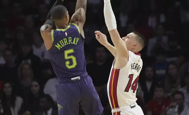 New Orleans Pelicans guard Dejounte Murray (5) shoots as Miami Heat guard Tyler Herro (14) defends during the first half of an NBA basketball game, Wednesday, Jan. 1, 2025, in Miami. (AP Photo/Lynne Sladky)