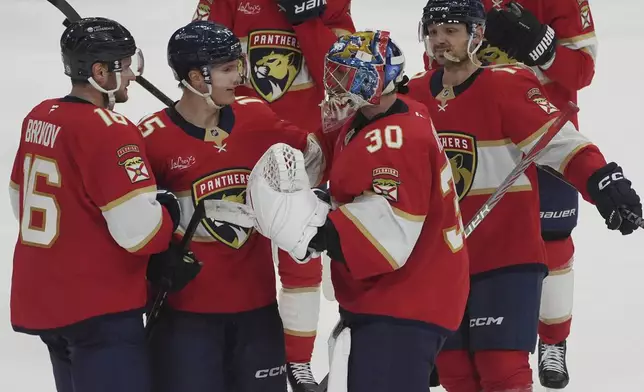 Florida Panthers goaltender Spencer Knight (30) celebrates with the team after defeating the Pittsburgh Penguins in a shootout at an NHL hockey game, Friday, Jan. 3, 2025, in Sunrise, Fla. (AP Photo/Marta Lavandier)