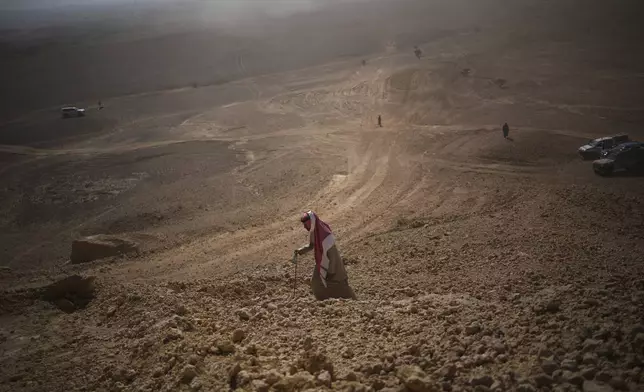 A man climbs to watch the drivers during the ninth stage of the Dakar Rally between Riyadh and Haradh, Saudi Arabia, Tuesday, Jan. 14, 2025. (AP Photo/Christophe Ena)
