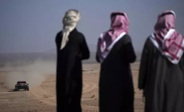 Spectators watch drivers compete during the sixth stage of the Dakar Rally between Hail and Al Duwadimi, Saudi Arabia, Saturday, Jan. 11, 2025. (AP Photo/Christophe Ena)