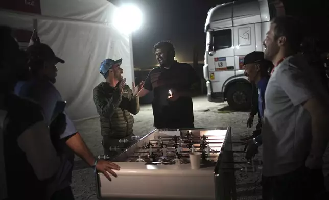 Workers at the bivouac play table soccer after the tenth stage of the Dakar Rally between Haradh and Shubaytah, Saudi Arabia, Wednesday, Jan. 15, 2025. (AP Photo/Christophe Ena)