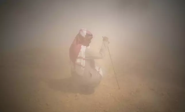 A man protects himself from dust during the ninth stage of the Dakar Rally between Riyadh and Haradh, Saudi Arabia, Tuesday, Jan. 14, 2025. (AP Photo/Christophe Ena)