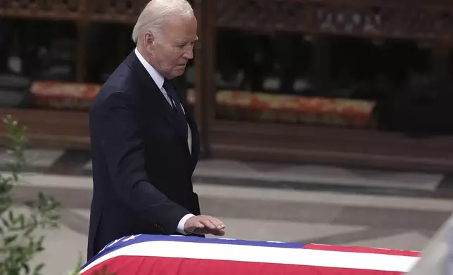 President Joe Biden touches the casket of former President Jimmy Carter during a state funeral service at Washington National Cathedral in Washington, Thursday, Jan. 9, 2025. (AP Photo/Jacquelyn Martin)