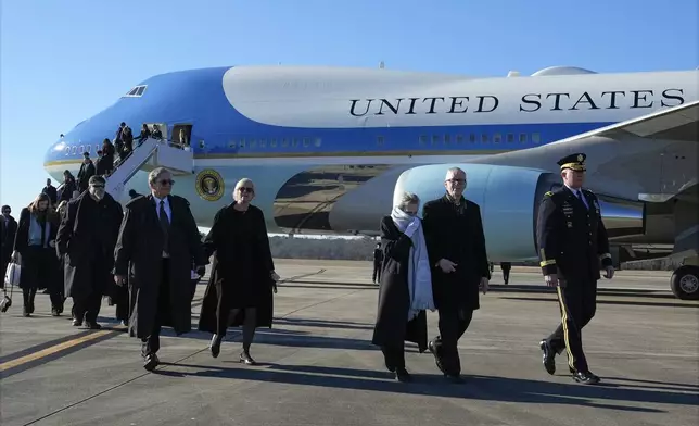 Maj. Gen. Trevor Bredenkamp, commanding general of the Joint Task Force-National Capital Region and the U.S. Army Military District of Washington, escorts Jack Carter and his wife Liz, and James "Chip" Carter and his wife Becky, and other family members, as they arrive before the flag-draped casket of former President Jimmy Carter is carried by a joint services body bearer team from Special Air Mission 39 at Lawson Army Airfield, in Fort Moore, Ga., Thursday, Jan. 9, 2025. (AP Photo/Alex Brandon, Pool)