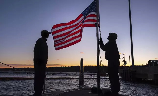 Sailors aboard Virginia-class attack submarine USS Virginia lower the flag from half mast during evening colors at the Naval Submarine Base New London, Thursday, Jan. 9, 2025, in Groton, Conn. (AP Photo/Julia Demaree Nikhinson)