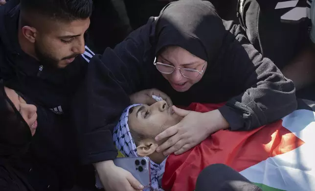 Relatives mourn over the body of Palestinian Muhammad Abu Amer, 18, who was killed at night during an Israeli army raid at his funeral in the West Bank refugee camp of Balata, Nablus, Saturday, Jan. 4, 2025. (AP Photo/Majdi Mohammed)