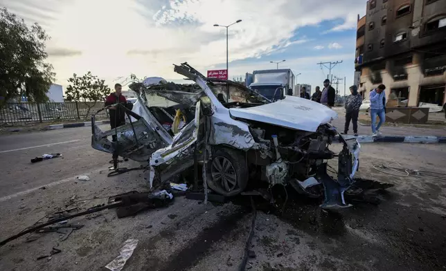 Palestinians inspect a car targeted in an overnight Israeli airstrike that killed its occupants in the town of Khan Younis, southern Gaza Strip, Saturday, Jan. 4, 2025. (AP Photo/Abdel Kareem Hana)