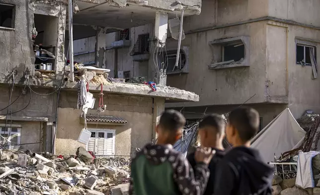 Palestinians look at a damaged residential building following an overnight Israeli strike in Deir al-Balah, Gaza Strip, Wednesday, Jan. 8, 2025. (AP Photo/Abdel Kareem Hana)