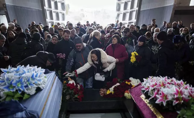 People attend the funeral ceremony of neurobiologist Ihor Zyma and his wife, biologist Olesia Sokur, who were killed by a Russian strike on Jan. 1, in Kyiv Monday, Jan. 6, 2025. (AP Photo/Evgeniy Maloletka)