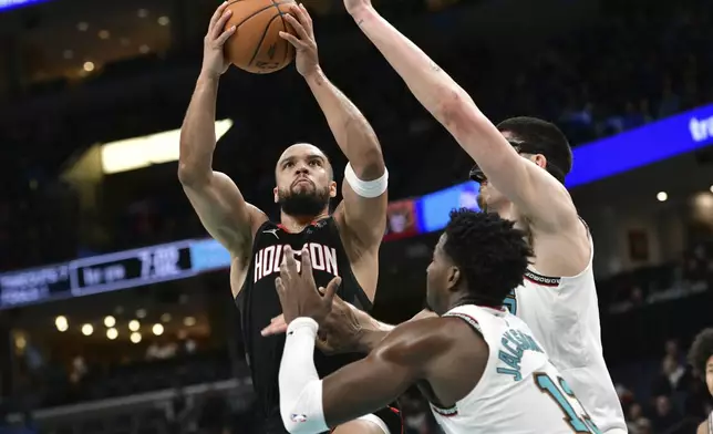 Houston Rockets forward Dillon Brooks (9) shoots agains tMemphis Grizzlies forward Jaren Jackson Jr. (13) and center Zach Edey, right, in the first half of an NBA basketball game Thursday, Jan. 30, 2025, in Memphis, Tenn. (AP Photo/Brandon Dill)