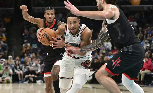 Memphis Grizzlies guard Desmond Bane, center, handles the ball between Houston Rockets center Steven Adams, right, and guard Jalen Green, left, in the second half of an NBA basketball game Thursday, Jan. 30, 2025, in Memphis, Tenn. (AP Photo/Brandon Dill)