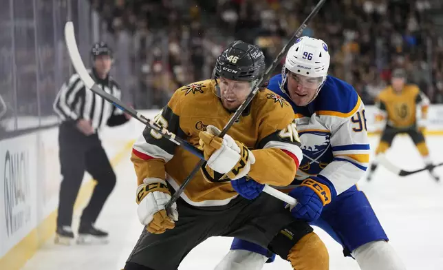 Buffalo Sabres right wing Nicolas Aube-Kubel (96) lifts the stick of Vegas Golden Knights right wing Jonas Rondbjerg (46) during the second period of an NHL hockey game, Saturday, Jan. 4, 2025, in Las Vegas. (AP Photo/Lucas Peltier)