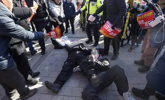 Demonstrators supporting, bottom left, and opposing impeached South Korean President Yoon Suk Yeol lie down on the ground near the presidential residence in Seoul, South Korea, Friday, Jan. 10, 2025. (AP Photo/Ahn Young-joon)