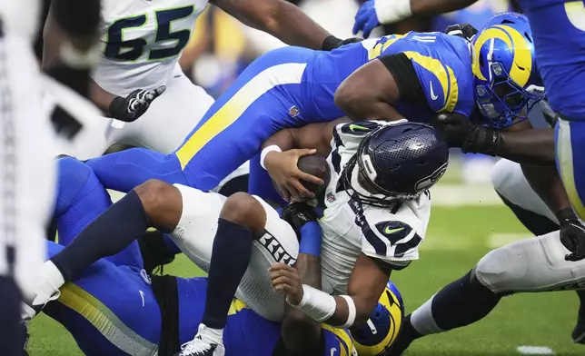 Seattle Seahawks quarterback Geno Smith is sacked by Los Angeles Rams defensive end Desjuan Johnson (94) during the first half of an NFL football game Sunday, Jan. 5, 2025, in Inglewood, Calif. (AP Photo/Eric Thayer)