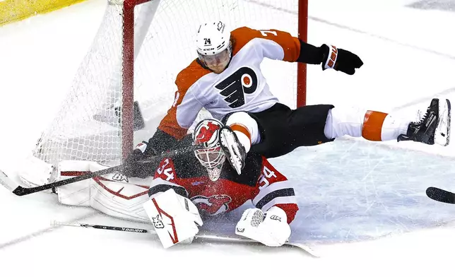 Philadelphia Flyers right wing Owen Tippett (74) collides with New Jersey Devils goaltender Jake Allen (34) during the third period of an NHL hockey game, Saturday, Jan. 18, 2025, in Newark, N.J. (AP Photo/Noah K. Murray)